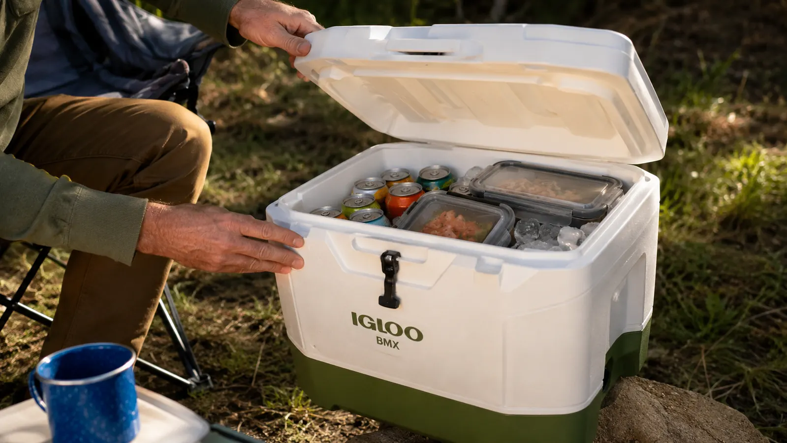 Hands opening the Igloo BMX cooler lid to reveal ice and food packed inside