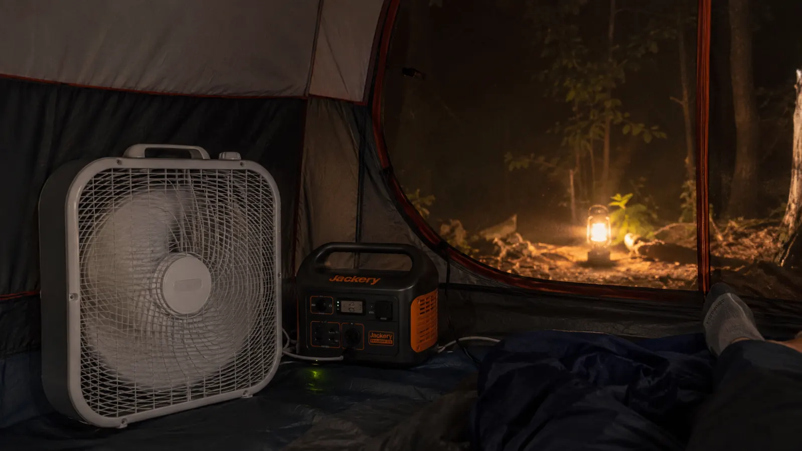 Jackery Explorer 300 powering a small box fan inside a screened camping tent at night