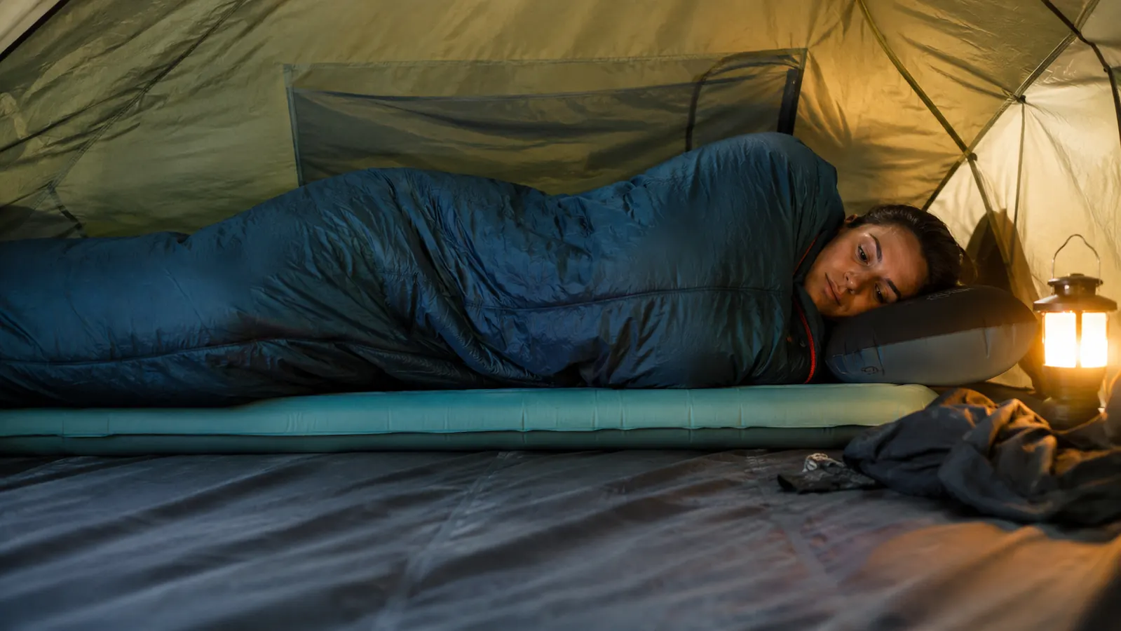 Side sleeper on a thin inflatable pad in a tent with visible space between hip and ground